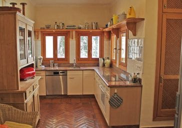 Corner kitchen with two windows and a wooden cupboard
