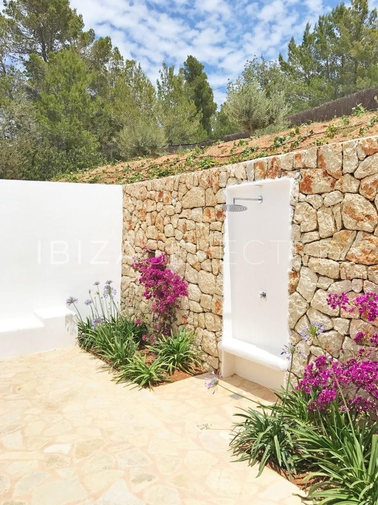 Outside shower within stone wall and flowers