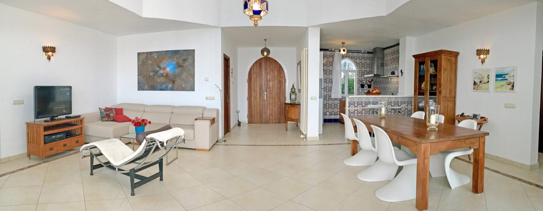 Living room with couch area at the left and dining area and open tiles' kitchen on the right