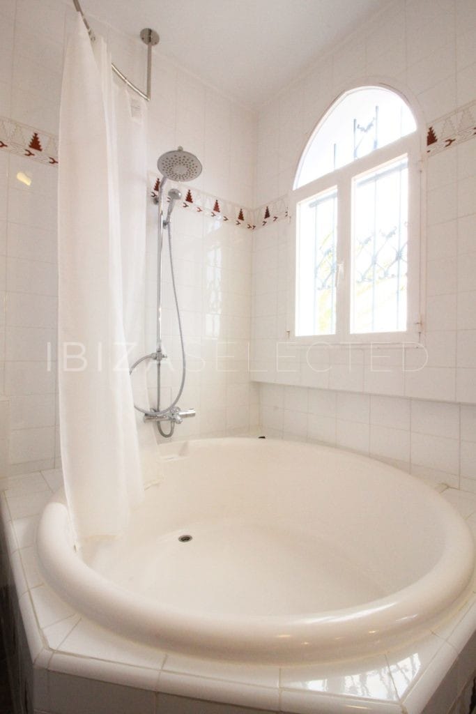 White round bathtub beside arched window
