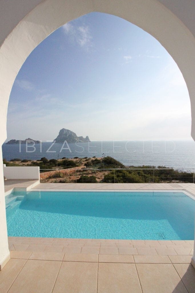 View through one arc of veranda's arc wall onto pool and rock in the sea