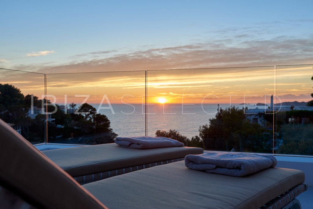 View of sea at sunset from terrace with loungers