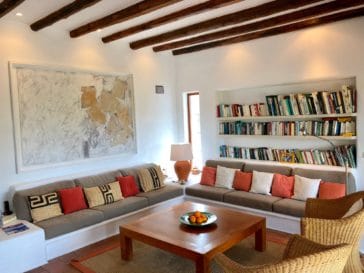 Rustic living room with wall couch suite, armchairs and wall shelf with books