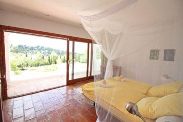 Bedroom with large door window and panorama view to green garden