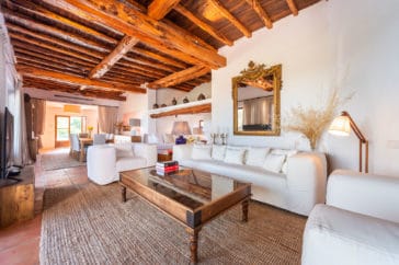 Rustic living room with white lounge suite and wooden beam roof