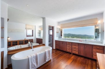 Bathroom with double vanity, wooden sink cabinets and oval bathtub