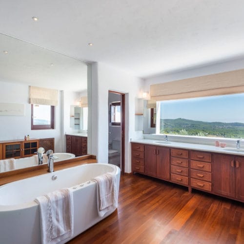 Bathroom with double vanity, wooden sink cabinets and oval bathtub