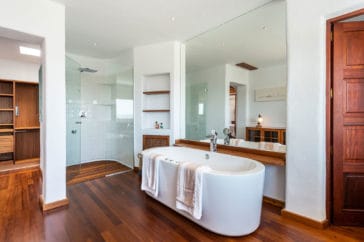 Bathroom with oval bathtub and walk-in shower with wooden floor in Blakstad-style