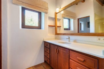 Bathroom with one sink, wooden sink cabinets and little window