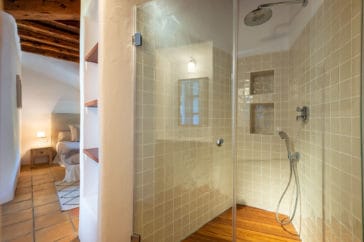Walk-in shower with wooden floor of open en-suite bathroom