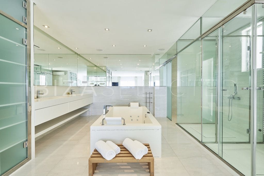 Spacious modern spa-bathroom with central jacuzzi bathtub and glass door showers