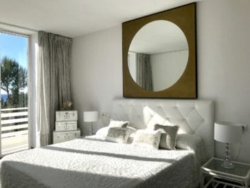 Double bedroom with round mirror and access to terrace