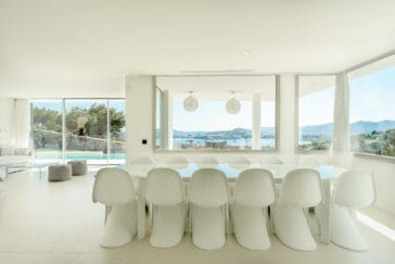 White dining table with white chairs in a corner of panoramic views living room