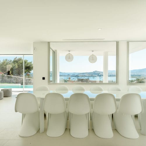 White dining table with white chairs in a corner of panoramic views living room