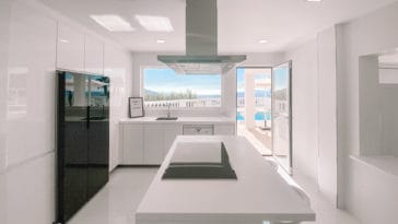 White modern kitchen with kitchen centre and access to pool terrace