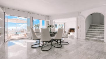 Round glass dining table with white chairs in the living room parallel to pool terrace