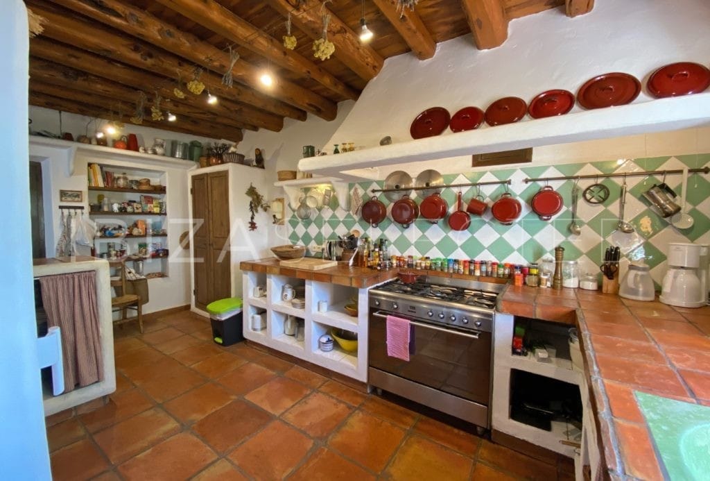 Kitchen in rustic style with open cupboards and and pots and accessories hanging on the wall