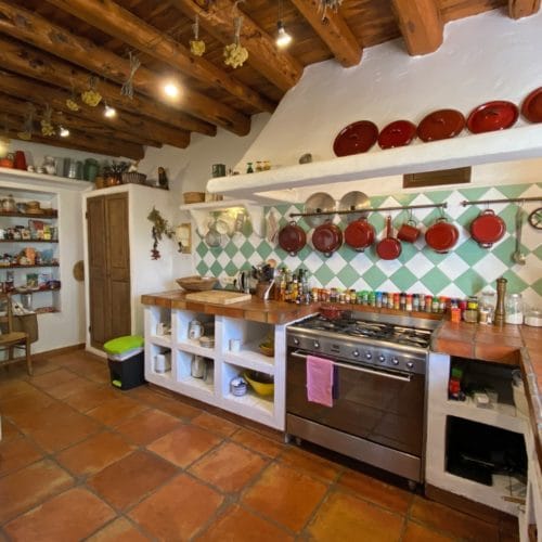 Kitchen in rustic style with open cupboards and and pots and accessories hanging on the wall