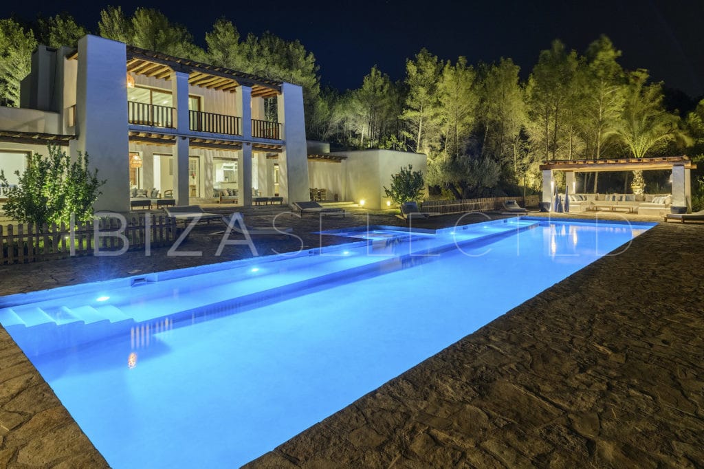 Frontal side view by night of villa with swimming pool and its chill zone