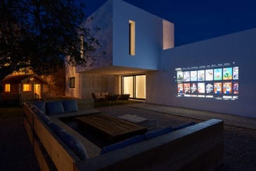 Outdoor cinema projected on house's wall with corner sofa