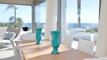 Look from inner wooden dining table through the glass front to the near sea