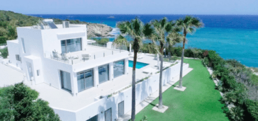 Rear side view of luxury villa on 3 floors surrounded by lawn garden next to sea with stunning views