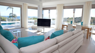 Living room with corner sofa in front of large windows with views to pool and sea