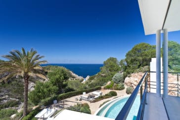 Views from upper terrace overlooking pool and garden, rocks and trees through to the sea