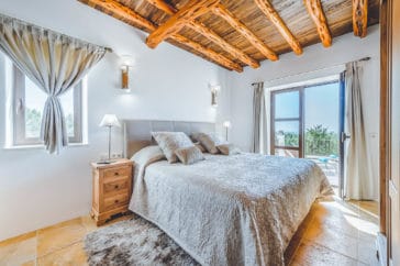 Double bedroom with wooden roof beams and access to terrace