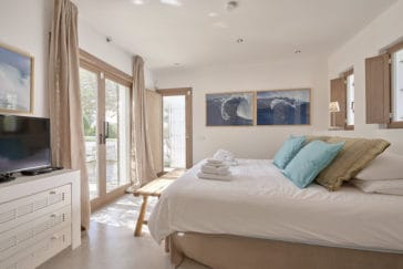 Natural style double bedroom with glass door that leads to terrace and 2 opposite windows