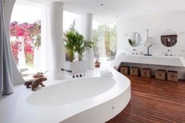 Spacious light bathroom with big window wall, a white oval sink and double make-up vanity