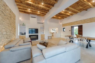 Living room with sofa, stone wall, wooden beams in Blakstad style zone to the entrance