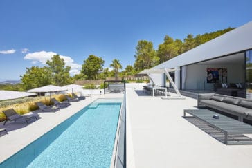 Pool outdoor area with square pool, a modern covered dining area, sun loungers with parasols and a sofa with table