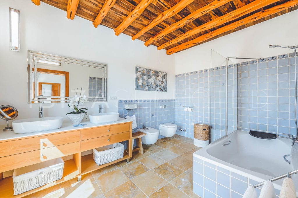 Spacious bathroom with double vanity, hanging toilet and bidet and a square bathtub