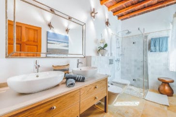 Bathroom with wooden double vanity, hanging toilet and bidet and walk in shower