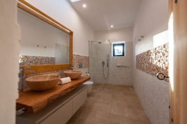 Blakstad-style bathroom with walk-in shower, with stone wall and wooden rustic elements
