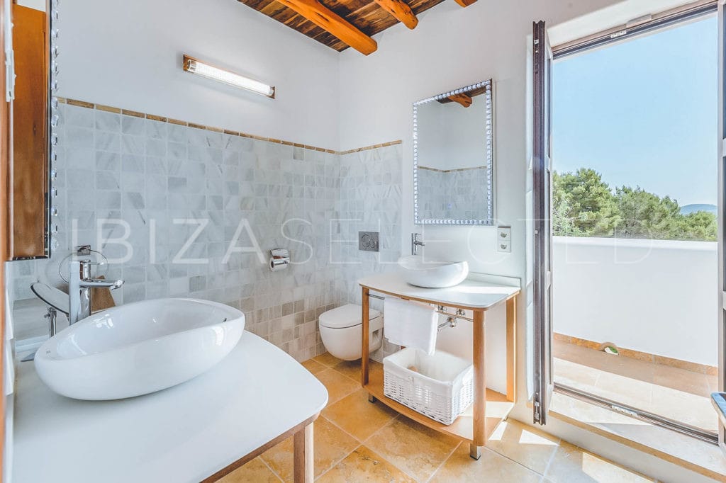 Bathroom with 2 individual washbasins and a hanging toilet with access to terrace