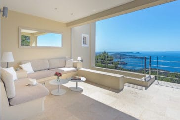 Corner sofa lounge beside a staircase leading down a with open amazing sea views