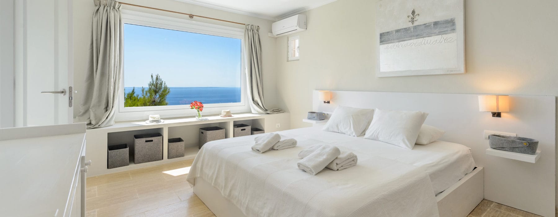 Double bedroom in white-beige design with a window that offers sea views