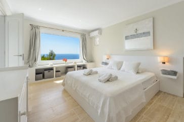 Double bedroom in white-beige design with a window that offers sea views