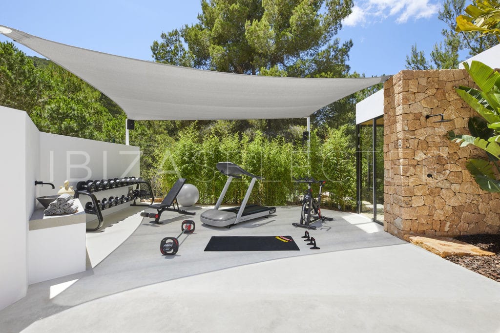 Equipped covered gym area with spinning bike, treadmill, dumbbells, gymnastic ball and abdominal muscle machine