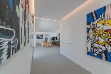 Interior corridor with modern pop-art paintings at both walls that lead to living room
