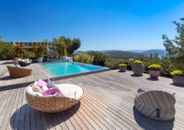 Infinity pool surrounded by a big wooden deck with views over the hills and to the sea