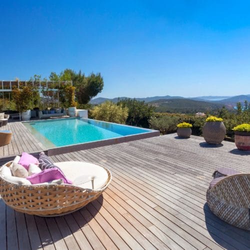 Infinity pool surrounded by a big wooden deck with views over the hills and to the sea