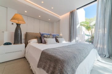 Modern bedroom with king-size bed and large wall window on ground floor