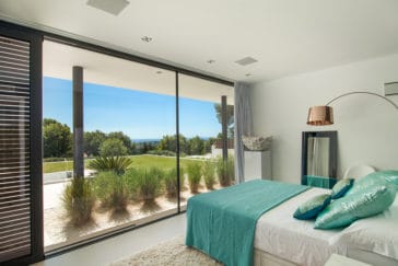 Double bedroom with large window wall with views to garden and pool