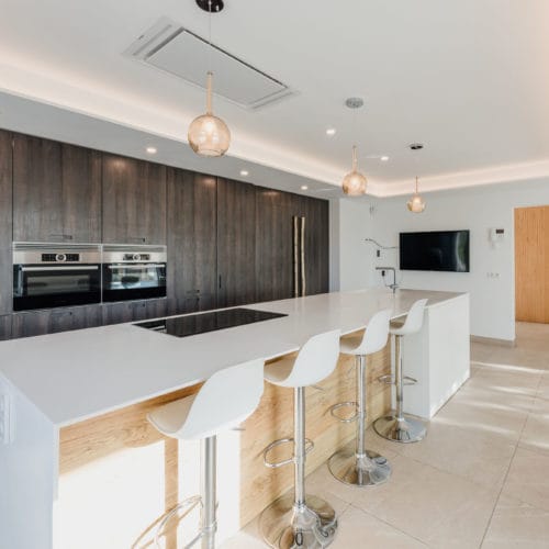 Modern kitchen with dark wooden cupboard wall and white kitchen centre