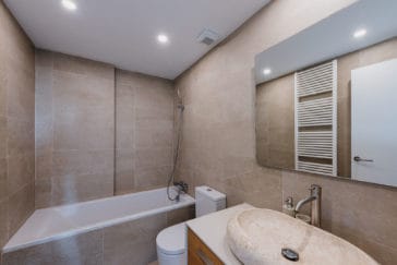 Bathroom with one sink and bathtub with grey beige tales