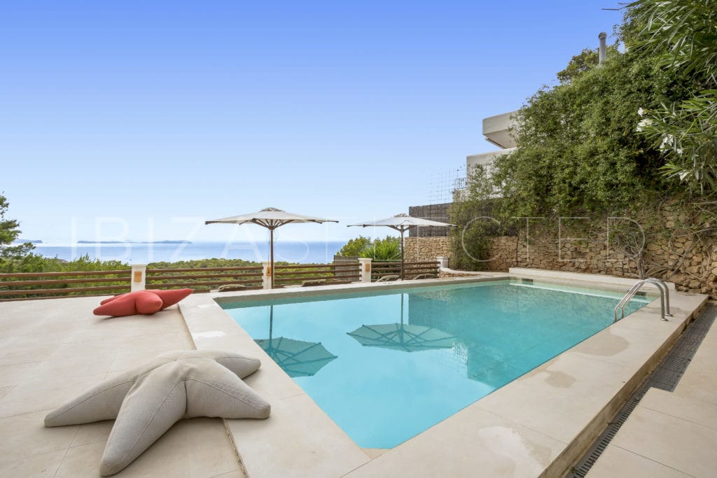 Pool with sea views fenced at the end with a stone wall and plants