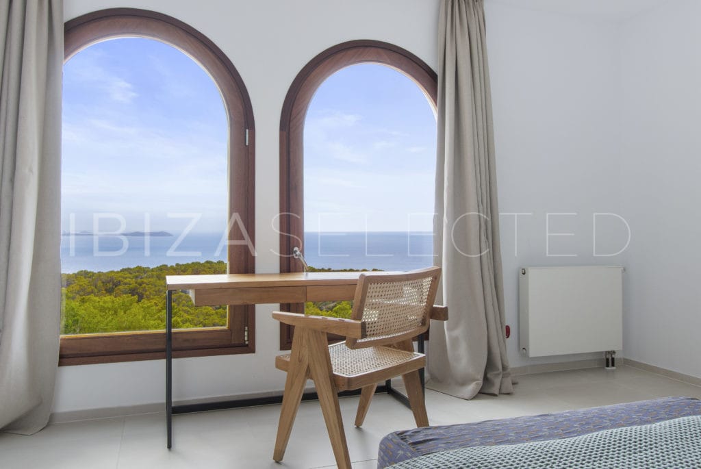 Wooden office desk in front of 2 huge arrow windows with sea view